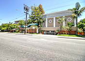 Thumbnail 5 of 30 - A brown building with a green awning is on the corner of a street.