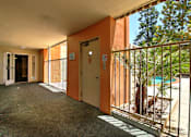 Thumbnail 9 of 30 - A long hallway with doors on both sides and a pool in the distance.