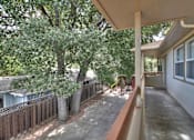 Thumbnail 5 of 22 - A patio with a white wall and a tree in the middle.