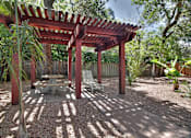 Thumbnail 4 of 22 - A red pergola with a white table and chairs is in a backyard.