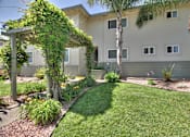 Thumbnail 3 of 22 - the front yard of the building with a lawn and palm trees