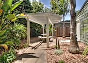 Thumbnail 7 of 27 - A patio with a white pergola and a bench.