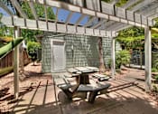 Thumbnail 8 of 27 - A patio with a table and chairs under a white pergola.