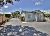 Thumbnail 2 of 15 - A house with a grey roof and white walls is surrounded by a fence and has a driveway in front.