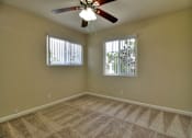 Thumbnail 9 of 15 - A room with a ceiling fan and carpeted floor.