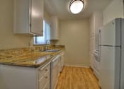 Thumbnail 7 of 21 - A kitchen with a granite countertop and white cabinets.