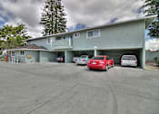 Thumbnail 5 of 21 - A parking lot with a red car and a white car in front of a building.