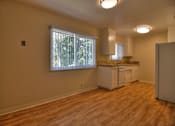 Thumbnail 6 of 21 - A kitchen area with wooden floors and white cabinets.