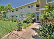 Thumbnail 4 of 21 - a sidewalk in front of a building with a lawn and plants
