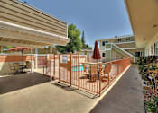 Thumbnail 8 of 21 - a patio with an umbrella and chairs and a pool