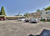 Thumbnail 11 of 33 - A parking lot with several cars and a building in the background.