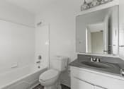 Thumbnail 17 of 47 - A white bathroom with a toilet, sink, and bathtub.