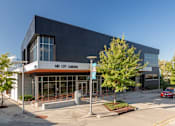 Thumbnail 1 of 16 - A modern building with a glass facade and a sign that reads