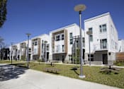 Thumbnail 9 of 16 - A row of modern white apartment buildings with balconies and a clear blue sky.
