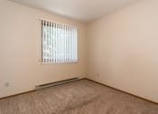 Thumbnail 9 of 12 - Grand Forks Kremer Apartments a bedroom with a large window and beige carpet