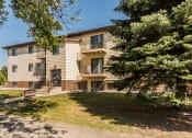 Thumbnail 12 of 12 - Grand Forks Kremer Apartments. The exterior of a three level apartment building with trees our front