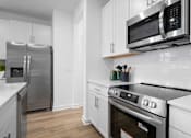 Thumbnail 6 of 33 - A modern kitchen with stainless steel appliances and white cabinets.