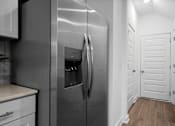 Thumbnail 7 of 33 - A stainless steel refrigerator in a kitchen with white cabinets.