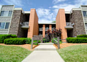 Thumbnail 1 of 9 - an exterior view of an apartment building with a sidewalk and grass