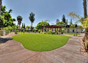 Thumbnail 7 of 17 - A courtyard with a green lawn and a red building in the background.