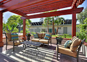 Thumbnail 9 of 17 - A patio with a red pergola and furniture.
