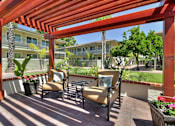 Thumbnail 10 of 17 - A patio with a red pergola and chairs.
