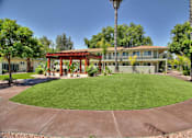 Thumbnail 16 of 17 - A building with a red roof is surrounded by a green lawn and trees.