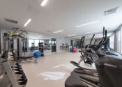 Thumbnail 16 of 24 - Bright, well-equipped fitness center with rows of cardio machines