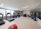 Thumbnail 23 of 24 - Modern fitness space with cardio equipment and stretching area