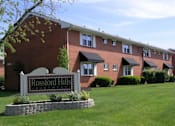 Thumbnail 1 of 16 - A brick building with a sign that says Rossford Hills Apartment.