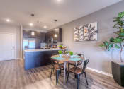 Thumbnail 28 of 78 - a dining area with a table and chairs and a kitchen in the background  at EdgeWater at City Center, Lenexa, 66219