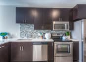 Thumbnail 58 of 78 - a kitchen with dark cabinets and stainless steel appliances  at EdgeWater at City Center, Lenexa, KS