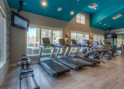 Thumbnail 46 of 78 - a room filled with cardio equipment and a flat screen tv  at EdgeWater at City Center, Lenexa, 66219
