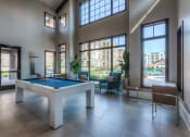 Thumbnail 39 of 78 - a pool table in the clubhouse with floor to ceiling windows  at EdgeWater at City Center, Lenexa