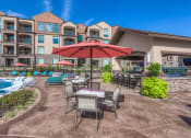 Thumbnail 6 of 78 - a patio with a table and chairs and a pool in front of a building  at EdgeWater at City Center, Lenexa, KS