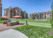 Thumbnail 19 of 78 - a grassy area with couches and umbrellas in front of an apartment complex  at EdgeWater at City Center, Lenexa, KS