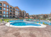Thumbnail 12 of 78 - a swimming pool with lounge chairs and umbrellas in front of an apartment building  at EdgeWater at City Center, Lenexa, 66219