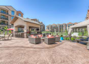 Thumbnail 16 of 78 - table and chair with grill and seating around a firepit with apartments in background  at EdgeWater at City Center, Kansas