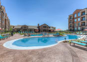 Thumbnail 14 of 78 - a swimming pool with chaise lounge chairs and a resort style building in the background  at EdgeWater at City Center, Kansas, 66219