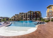Thumbnail 3 of 42 - a swimming pool with lounge chairs and umbrellas with an apartment building in the background  at WaterCrest at City Center, Lenexa, Kansas
