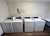 Thumbnail 12 of 21 - A room with two washing machines and a poster on the wall.
