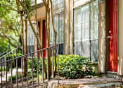 Thumbnail 27 of 27 - Building entrance with red door and metal railing at The Colony Apartments, Universal City, 78148