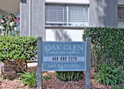 Thumbnail 7 of 28 - A sign for Oak Glen Apartment Homes stands in front of a building.