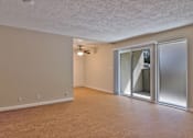 Thumbnail 15 of 28 - A room with a sliding glass door and a ceiling fan.