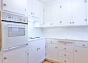 Thumbnail 10 of 28 - A white kitchen with a stove and oven.