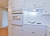 Thumbnail 11 of 28 - A white kitchen with a stove and oven.