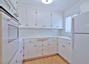 Thumbnail 12 of 28 - A white kitchen with wooden floors and white cabinets.
