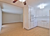 Thumbnail 13 of 28 - A kitchen with white cabinets and a wooden floor.