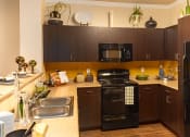 Thumbnail 46 of 55 - a kitchen with black appliances and brown cabinets
