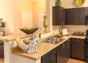 Thumbnail 26 of 55 - a kitchen with dark cabinets and a bowl of fruit on the counter